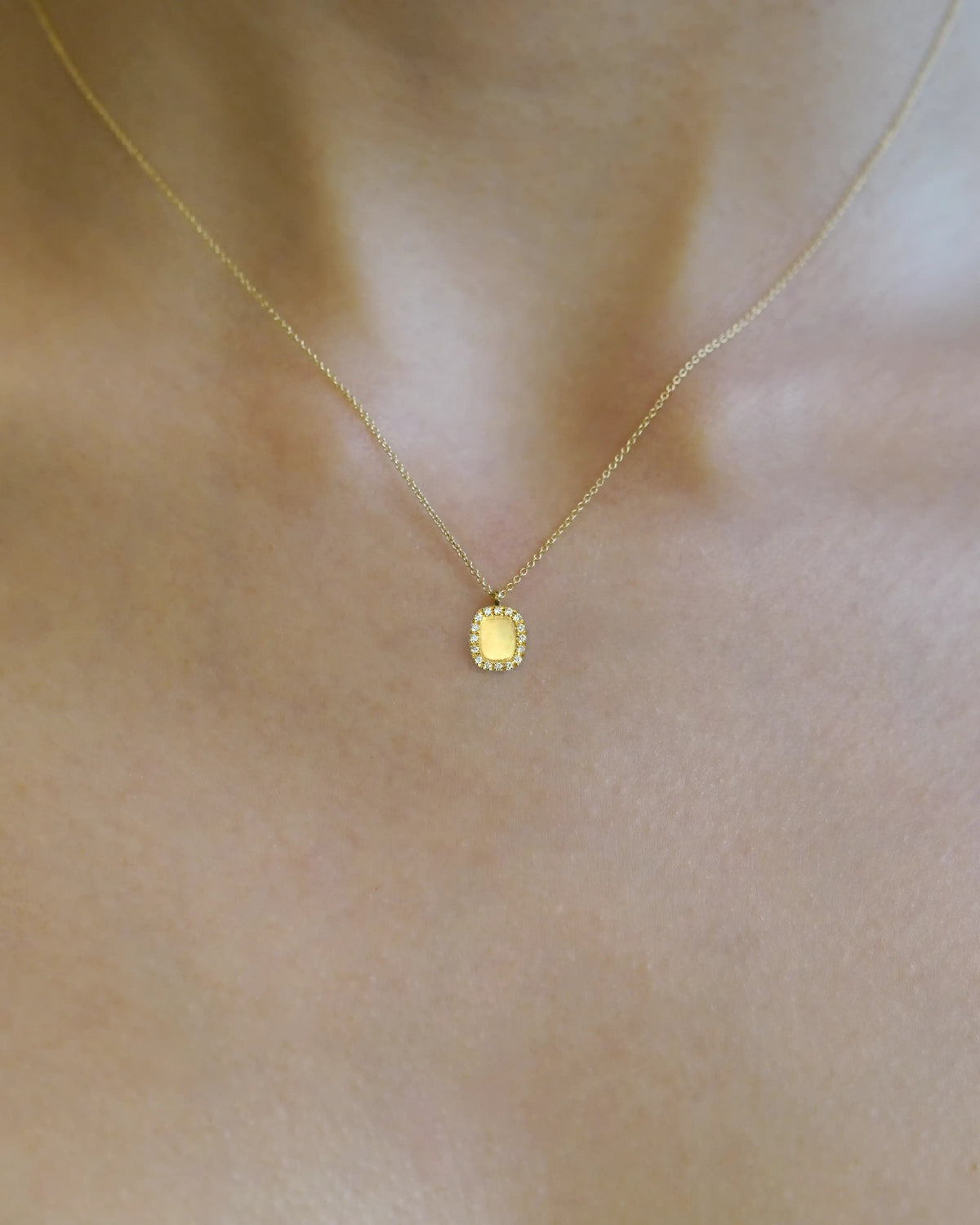 Yellow gold necklace with rectangular pendant with white diamond contour