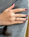 Gold ring with purple gemstone on woman's hand, grey sweater background, elegant jewelry