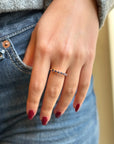 Hand wearing a delicate gold ring with blue gemstones, casual denim background